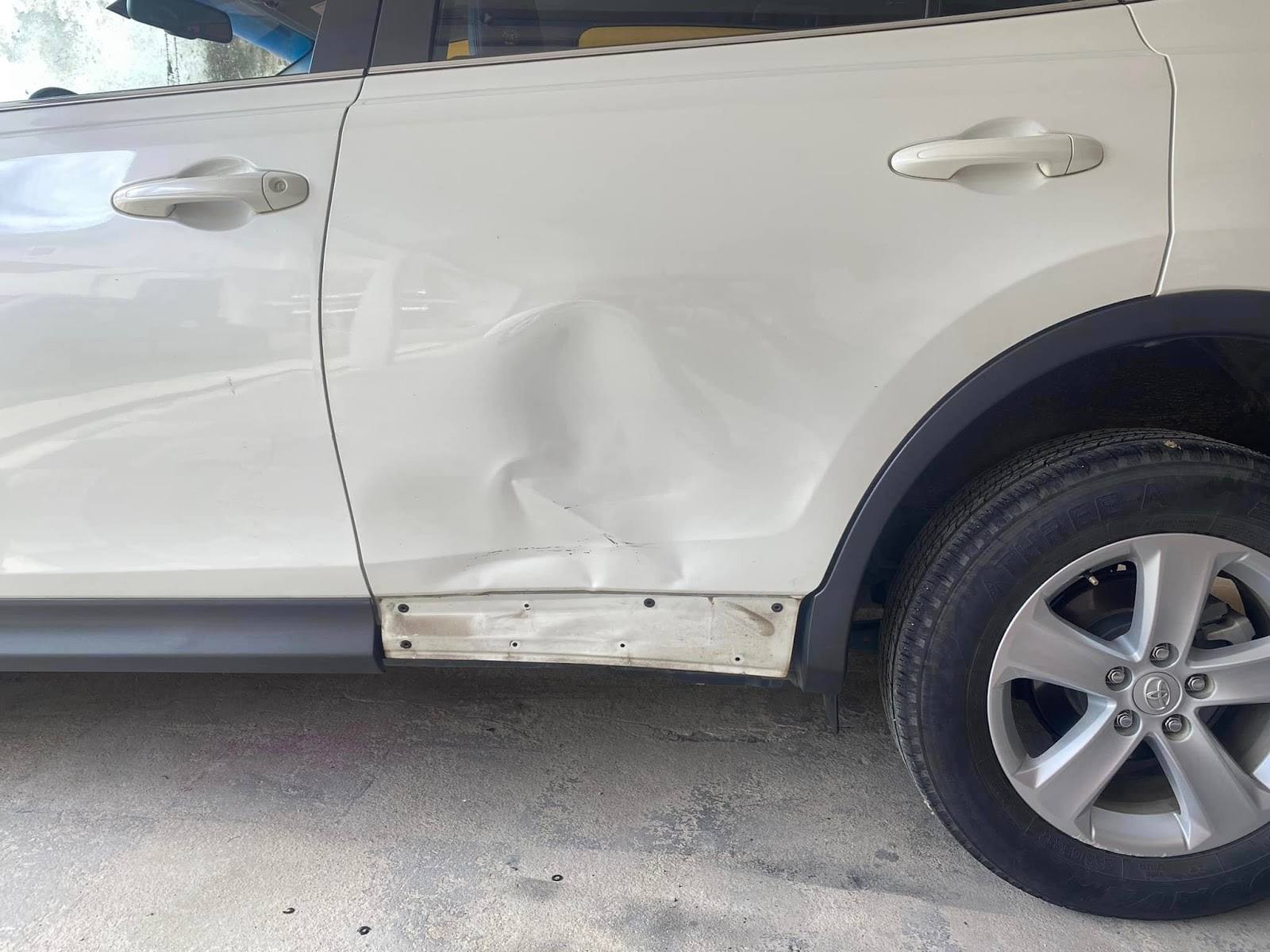 Amassado em porta de carro branco antes do reparo de martelinho de ouro